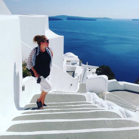 Bianca Marie Brookman | Greece Stairs Bianca Brookman walking up stairs in Greece white washed with Grecian buildings behind her on the left and the deep sea on the right.